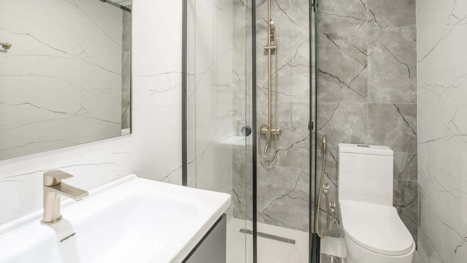Bright bathroom with glazed tile, grout lines, a sink, and a glass shower enclosure.