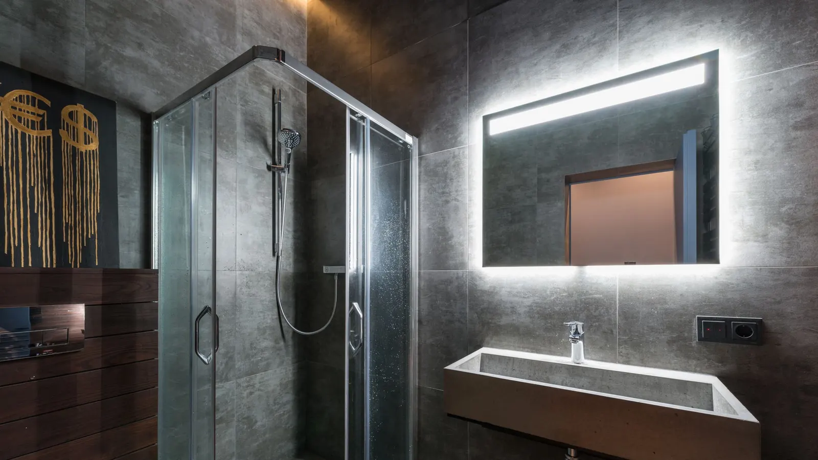 Dark tiled bathroom with a glass shower enclosure and visible metal hardware.