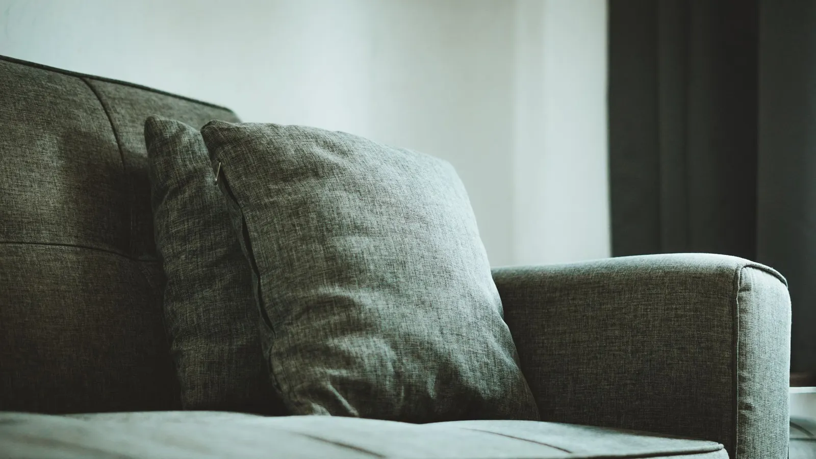 Close view of a gray fabric sofa with textured upholstery and cushions.