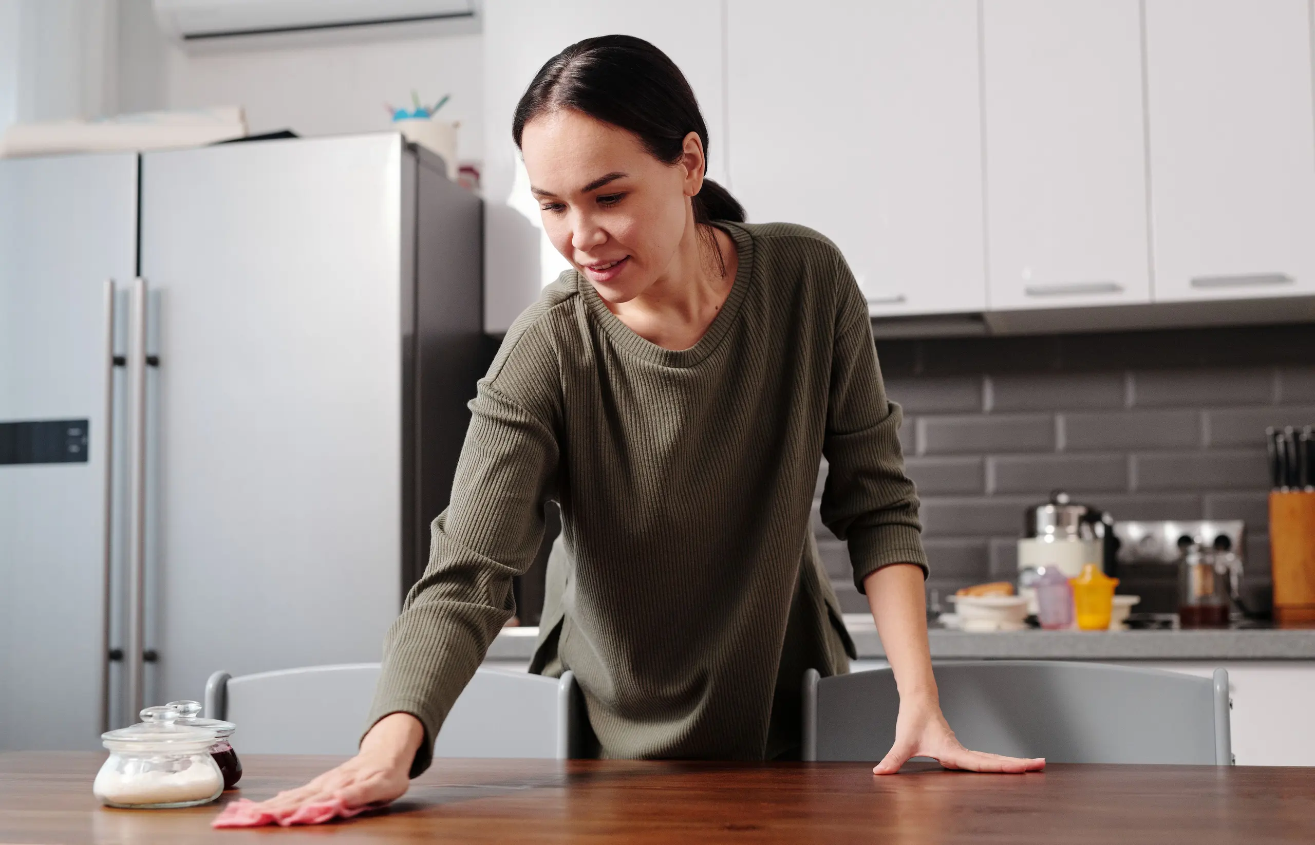 A person wiping a table in a bright home kitchen