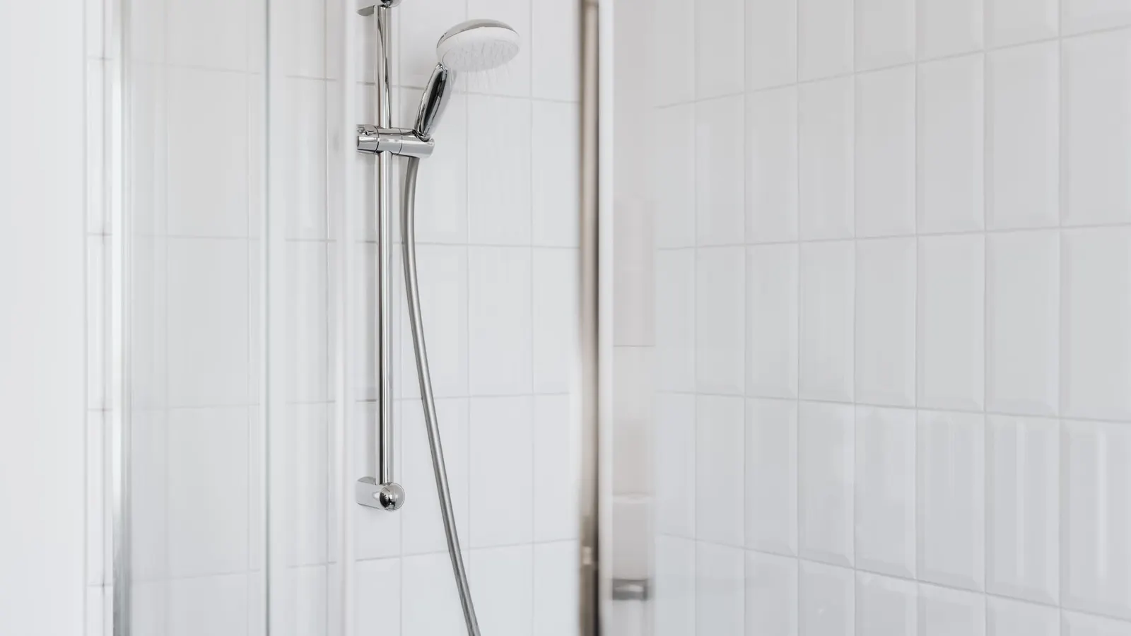 Stylish shower setup with chrome fixtures and clean white tiles.